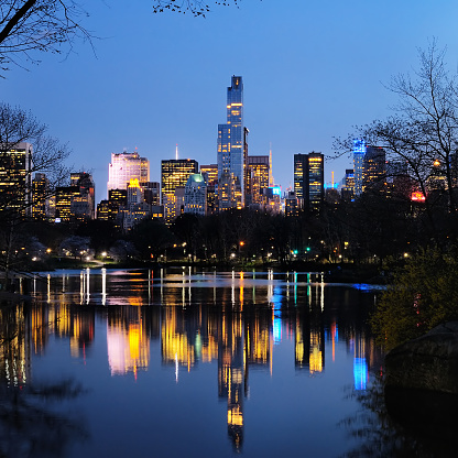 Central Park in dusk and buildings reflection in midtown Manhattan New York City