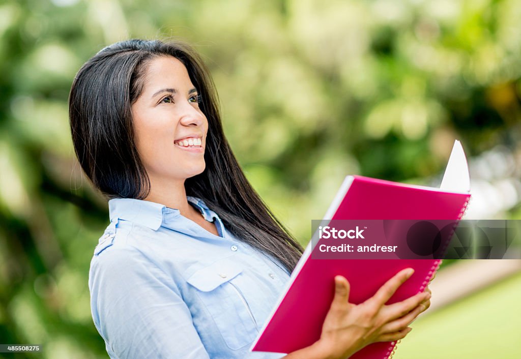 Happy female student Happy female student holding a notebook at the park Adult Stock Photo