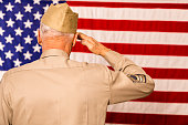 Military: Senior veteran in uniform saluting American flag.