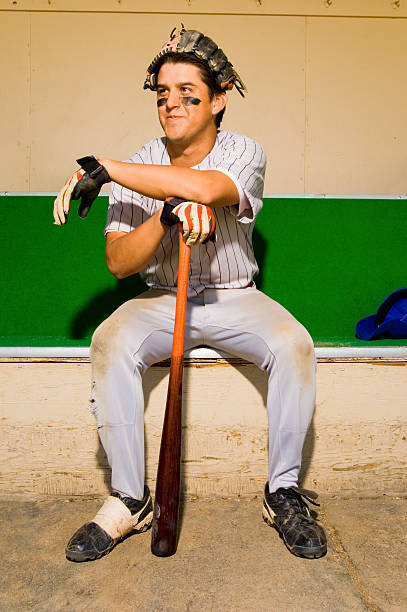 joueur de baseball de banc de touche avec chauve-souris - dugout baseball bench bat photos et images de collection