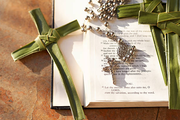 istock Palm cross, rosary beads sitting on an open Bible 485510070