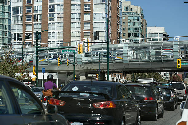 motorists i torowym w pobliżu głównych stacji kolejki napowietrznej skytrain street, vancouver - lee street station zdjęcia i obrazy z banku zdjęć