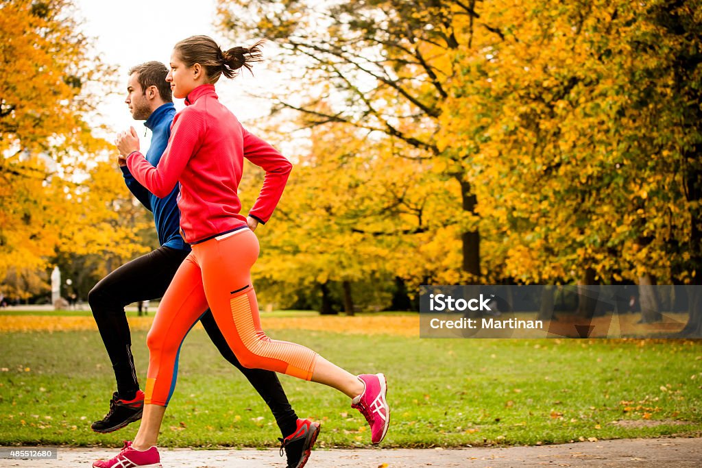 Couple jogging in autumn nature Running together - friends jogging together in park, rear view Couple - Relationship Stock Photo