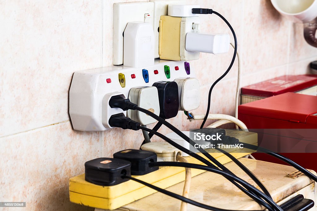 Multiple electricity plugs on adapter risk overloading and dange Multiple electricity plugs on adapter risk overloading and dangerous. Over-Burdened Stock Photo