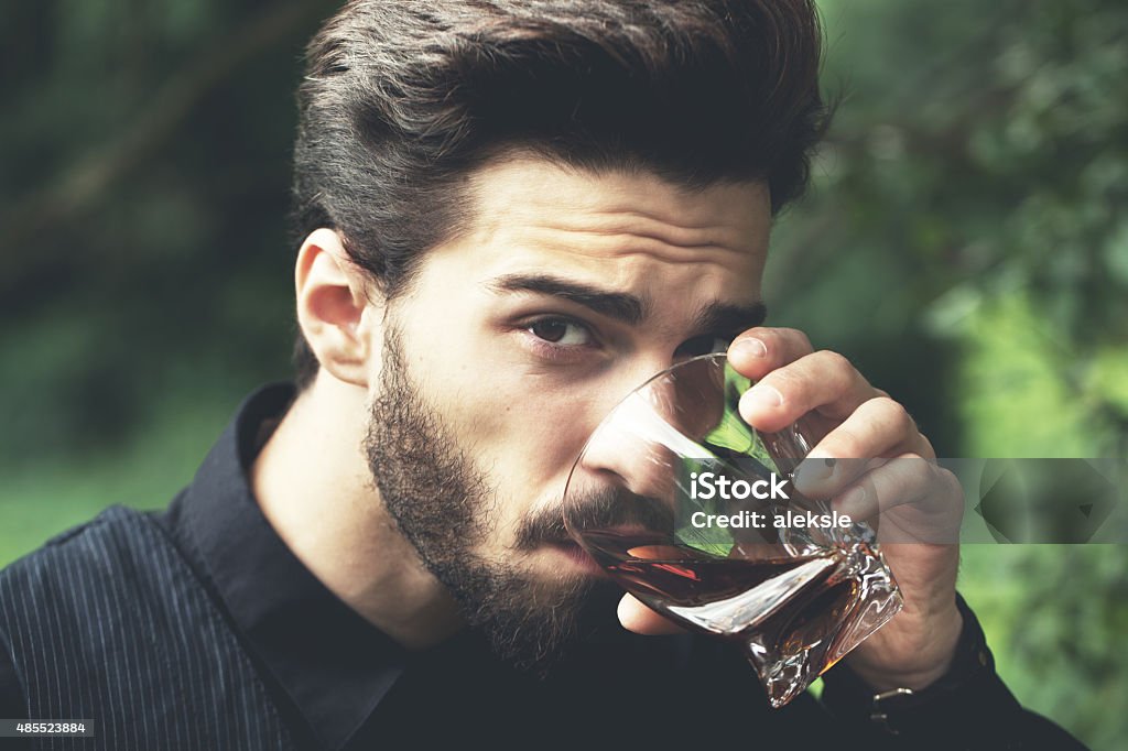 Bearded man with glass of whiskey. Bearded man posing outdoors with alcohol. Special toned image colors. Drinking Stock Photo