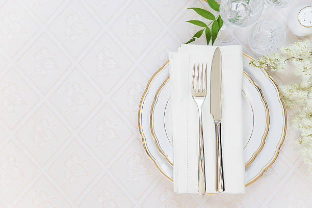Beautiful table setting Top view of the beautifully decorated table with white plates, crystal glasses, linen napkin, cutlery and white flower on luxurious tablecloths, with space for text white restaurant dishes stock pictures, royalty-free photos & images
