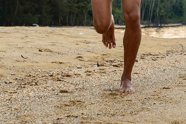 Barefoot running on beach at sunset. stock photo