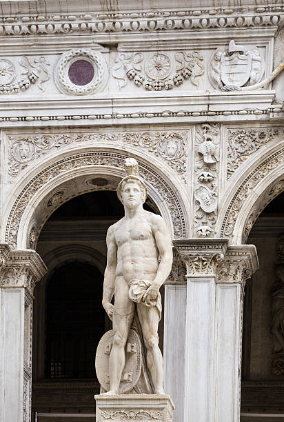 Doge's Palace  and Giants’ Staircase as seen from Courtyard, Venice, Italy. The Scala dei Giganti (Giants’ Staircase) is flanked by Mars and Neptune and framed by an arch. The Doge's Palace (Italian: Palazzo Ducale) was built in Venetian Gothic style in Piazza San Marco. The palace was the residence of the Doge of Venice, the supreme authority of the former Republic of Venice. It opened as a museum in 1923. Vivid blue sky is in background.