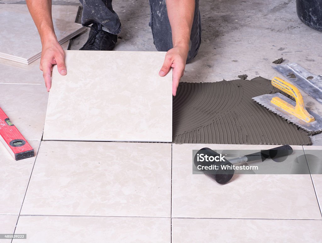 tile Tiler installing ceramic tiles on a floor 2015 Stock Photo