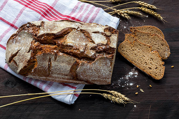 istock rustic bread and slices with wheat ears on dark wood 485539276