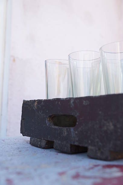 A set of drinking glasses standing on a wooden tray, photographed in Skagen in the North of Denmark on a sunny day, though standing in the shadow.