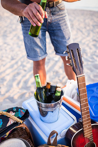 istock Man opening bottle of beer on the beach. 485544052