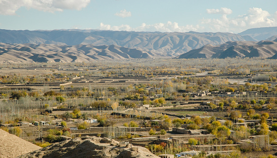 Maimana, the Uzbek capital of Faryab Province, North Western Afghanistan. It is a typical smaller town - a river runs through the centre, visible in the mid-ground. Tall poplar trees grow everywhere, used extensively for building.