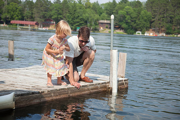 istock Young girl feeds fish from dock in Minnesota with dad 485551000