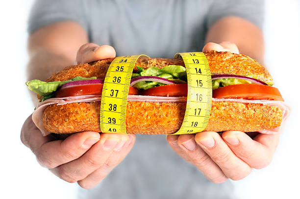 sandwich légumes recouvert de ruban à mesurer régime concept - food measuring hamburger dieting photos et images de collection