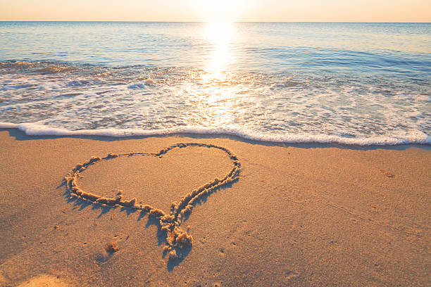 símbolo de corazón en la arena de la playa del mar - adorando a dios fotografías e imágenes de stock