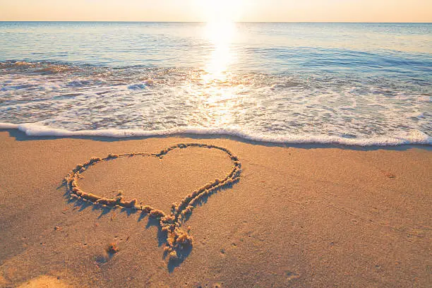 Photo of Heart symbol in the sand by the ocean