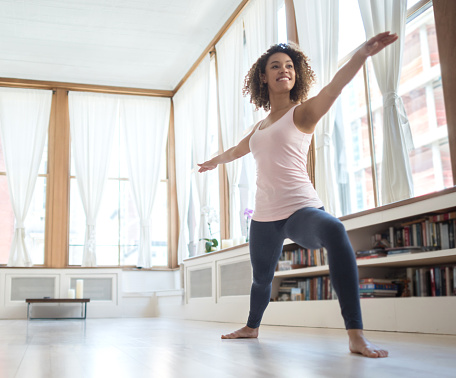 African American woman doing yoga at home and looking very happy - healthy lifestyle concepts