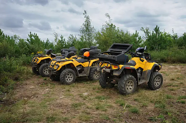 Three yellow atv parked on the top of the hill