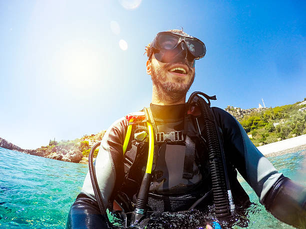 Smiling diver portrait at the sea shore. Young diver smiles while prepares for diving. scuba diving stock pictures, royalty-free photos & images
