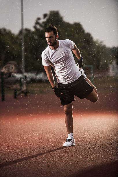 istock Young athletic man stretching his leg on a rain. 485580108