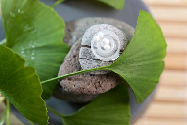 Pills with extract from the ginkgo in bottle and green leaves isolated on a white background.
