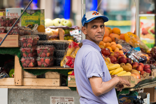 New York, USA - July 6, 2015: A street vendor selling fruit from a cart late in the day on Broadway in Manhattan.