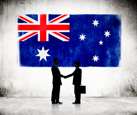 Two Businessmen Shaking Hands With Australian Flag As A Background