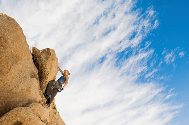 istock Girl Climbing Rock Against Cloudy Sky 485585563