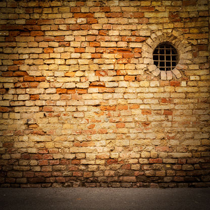 Old brick facade with a round window. Square shape.