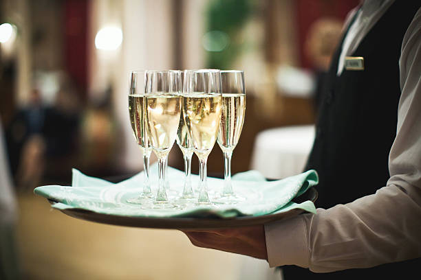 waiter serving champagne on a tray - 男侍應 圖片 個照片及圖片檔