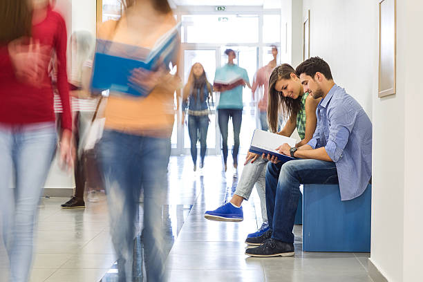 istock College students reading a book in university corridor. 485588636
