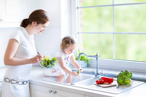 istock Mother and her daughter cooking salad in kitchen with window 485589209