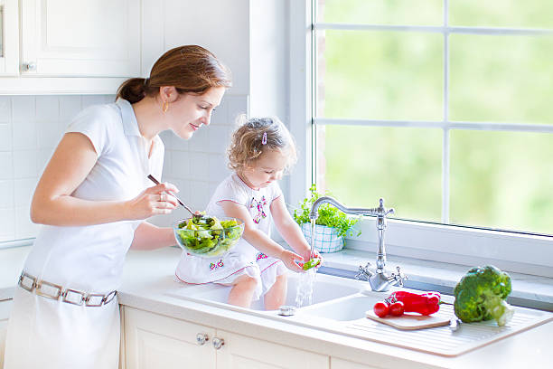 istock Mother and daughter in kitchen with big garden view window 485589211