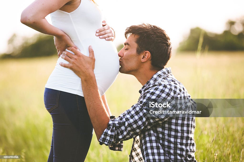 Young man kissing the belly of his pregnant woman Pregnant Stock Photo