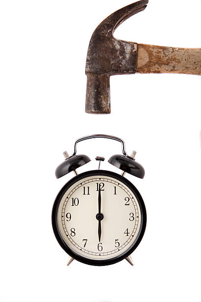 Alarm clock revenge. Hammer about to smash an alarm clock. Concept is anger due to alarm clock waking person up. smash alarm clock stock pictures, royalty-free photos & images