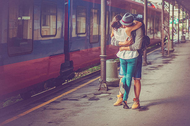 Portrait of happy woman and man embracing at railway platform stock photo