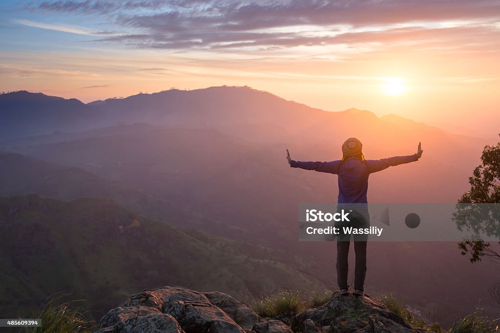 Happy celebrating winning success woman Happy celebrating winning success woman at sunset or sunrise standing elated with arms raised up above her head in celebration of having reached mountain top summit goal during hiking travel trek. 2015 Stock Photo