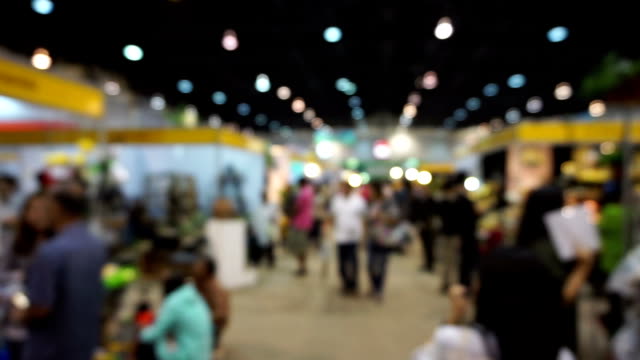 People walking in exhibition fair defocused background.