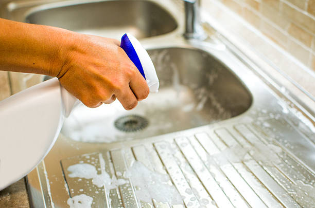 Woman doing chores in the kitchen at home , sink and faucet with spray cleaner