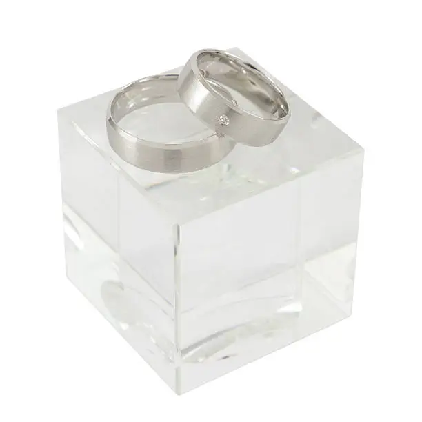 A pair of white gold rings on cubic glass isolated on white. 
