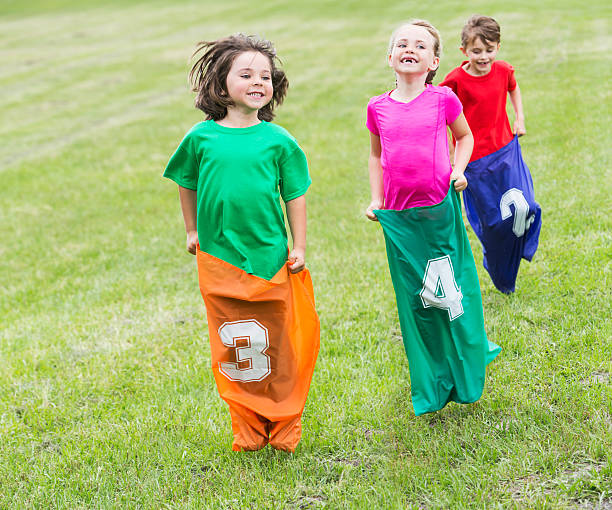 três crianças felizes em batata corrida de saco - child playing sack race sports race - fotografias e filmes do acervo