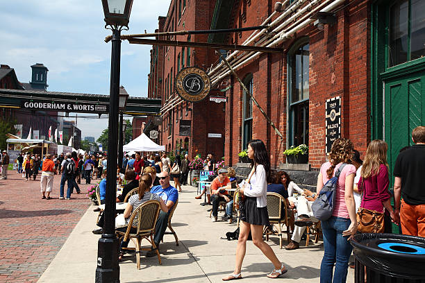 Toronto, Ontario, Canada - June 9, 2012: People enjoying the summer sun outdoors on the streets sitting in the Balzac's coffee-shop and walking in the Distillery District of Toronto, Canada 