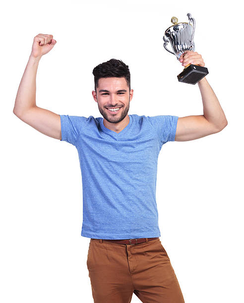 istock winning young casual man with a big trophy cup 485614119