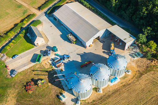 Aerial photo of modern farm, tractors, harvesters and agricultural equipment, barns and grain silos. ProPhoto RGB profile for maximum color fidelity and gamut.