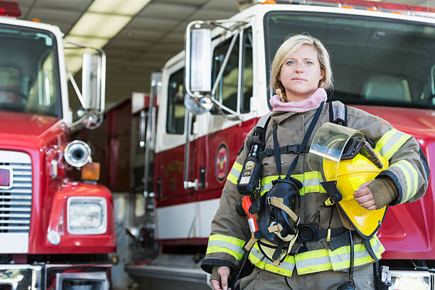 bombero mujer de pie delante de camión de bomberos - fire department heroes portrait occupation fotografías e imágenes de stock