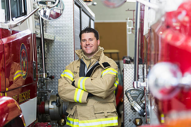 Fireman at station standing next to fire truck stock photo