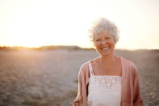 istock Cheerful old woman standing on the beach 485617021
