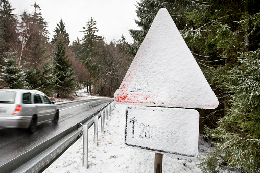 Snow-covered traffic sign, road - passing car, some motion blur
