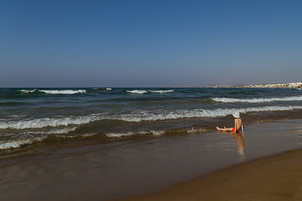 istock Child is sitting on the sand at the beach 485628532